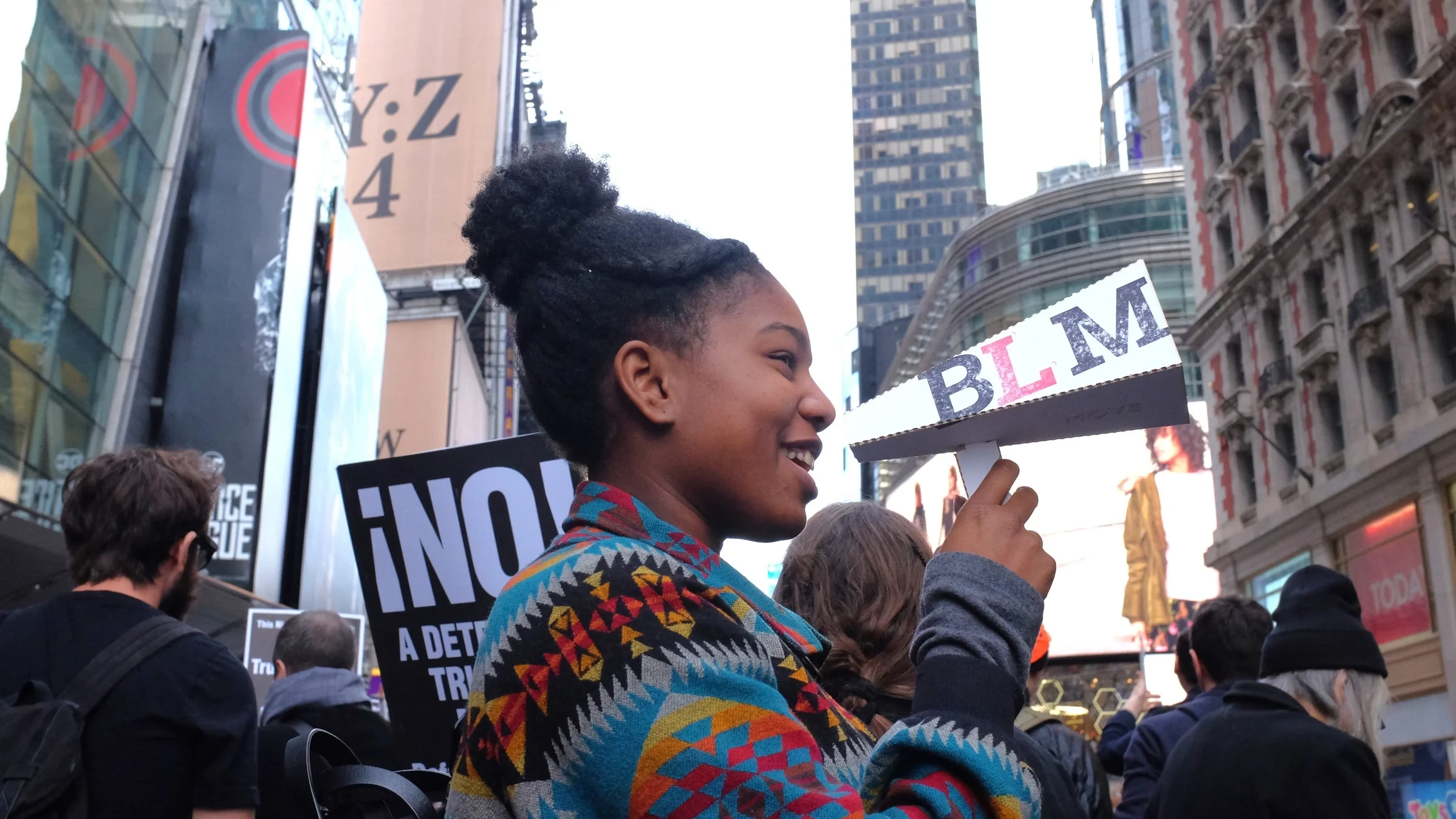 A protester holds a MOVE-branded "BLM" megaphone sign at a Times Square rally