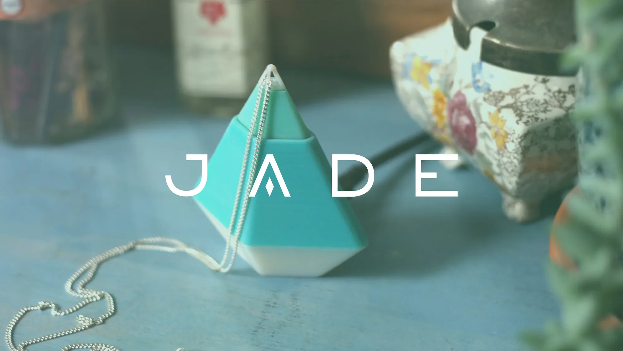 The Jade pendant and its charging stand, shown alongside its wordmark